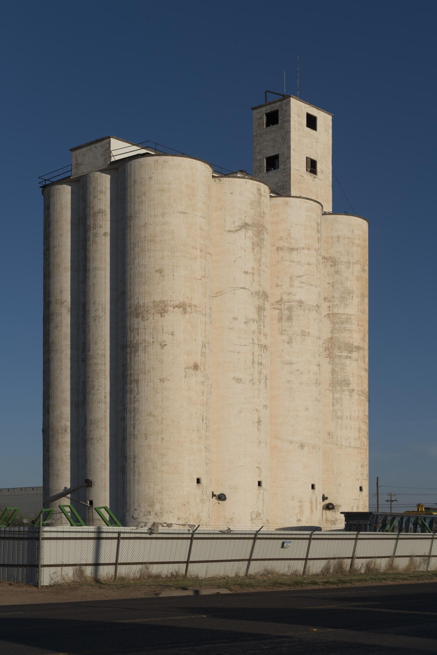 A tall white concrete grain elevator rises against a deep blue sky in Lamesa.